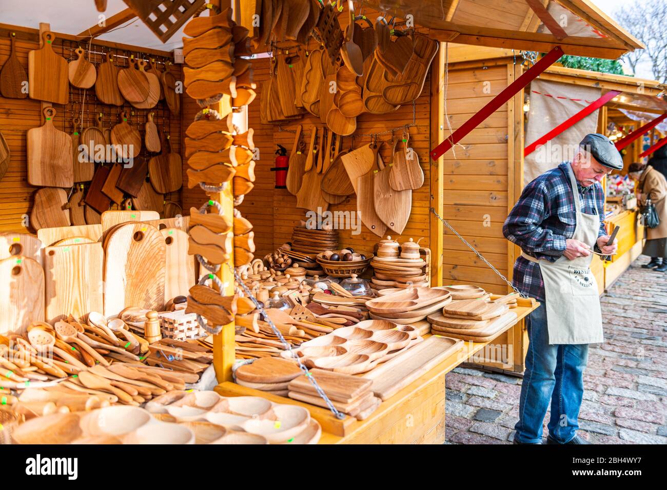 Warsaw, Poland - December 21, 2019: Christmas market stall in Warszawa old town with people senior man seller vendor in winter selling wood art Stock Photo
