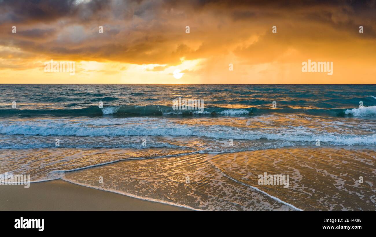 Beach under dramatic sky at sunset Stock Photo