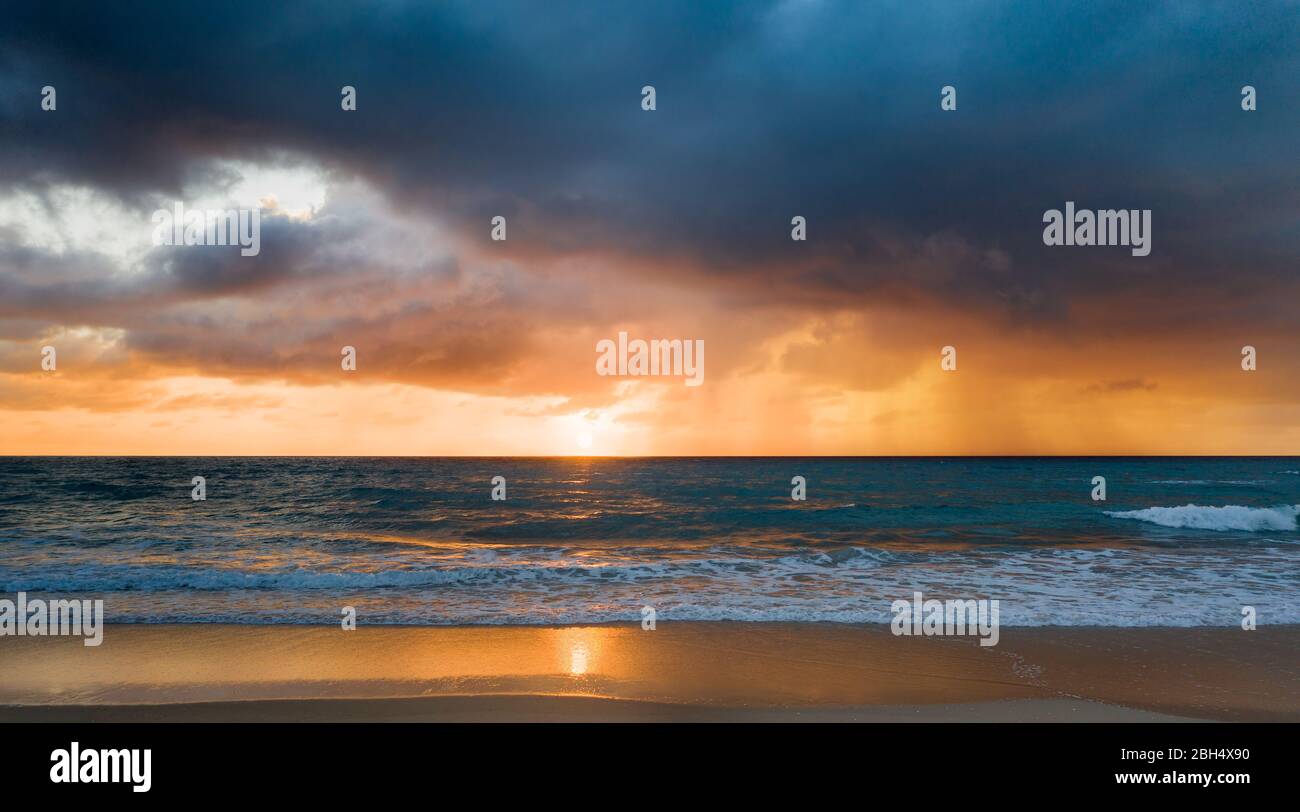 Beach under dramatic sky at sunset Stock Photo
