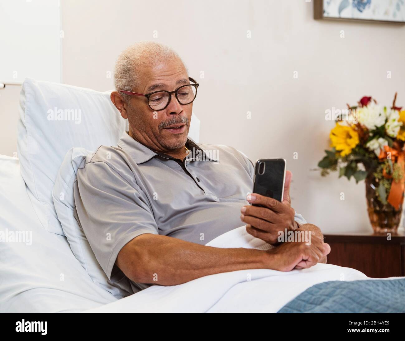 Senior man using smart phone in bed Stock Photo
