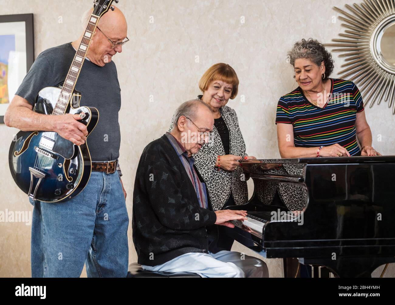 Senior people watching senior man playing piano Stock Photo