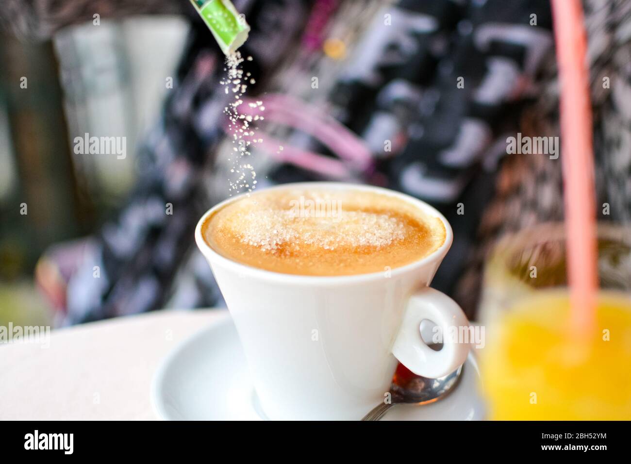 Pouring granulated sugar into a delicious cafe au lait, cafe creme or espresso at a Parisian cafe Stock Photo