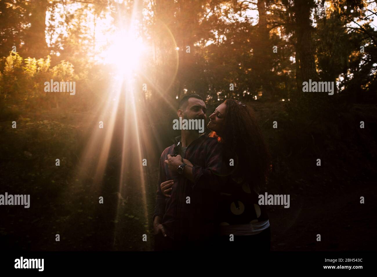 Smiling couple embracing by sunlight in forest Stock Photo