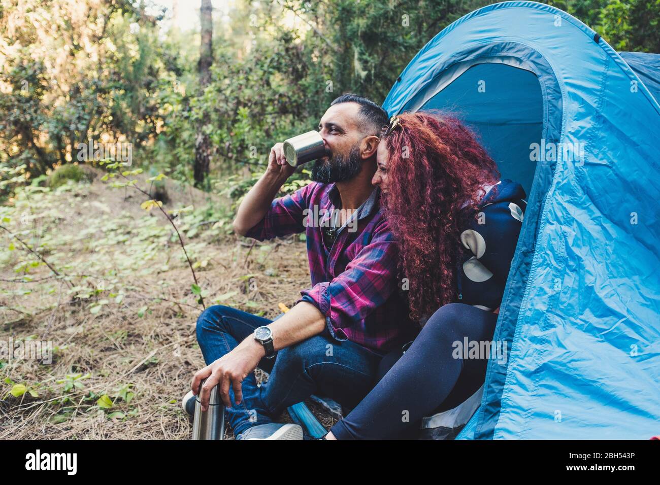 Smiling couple drinking by tent Stock Photo