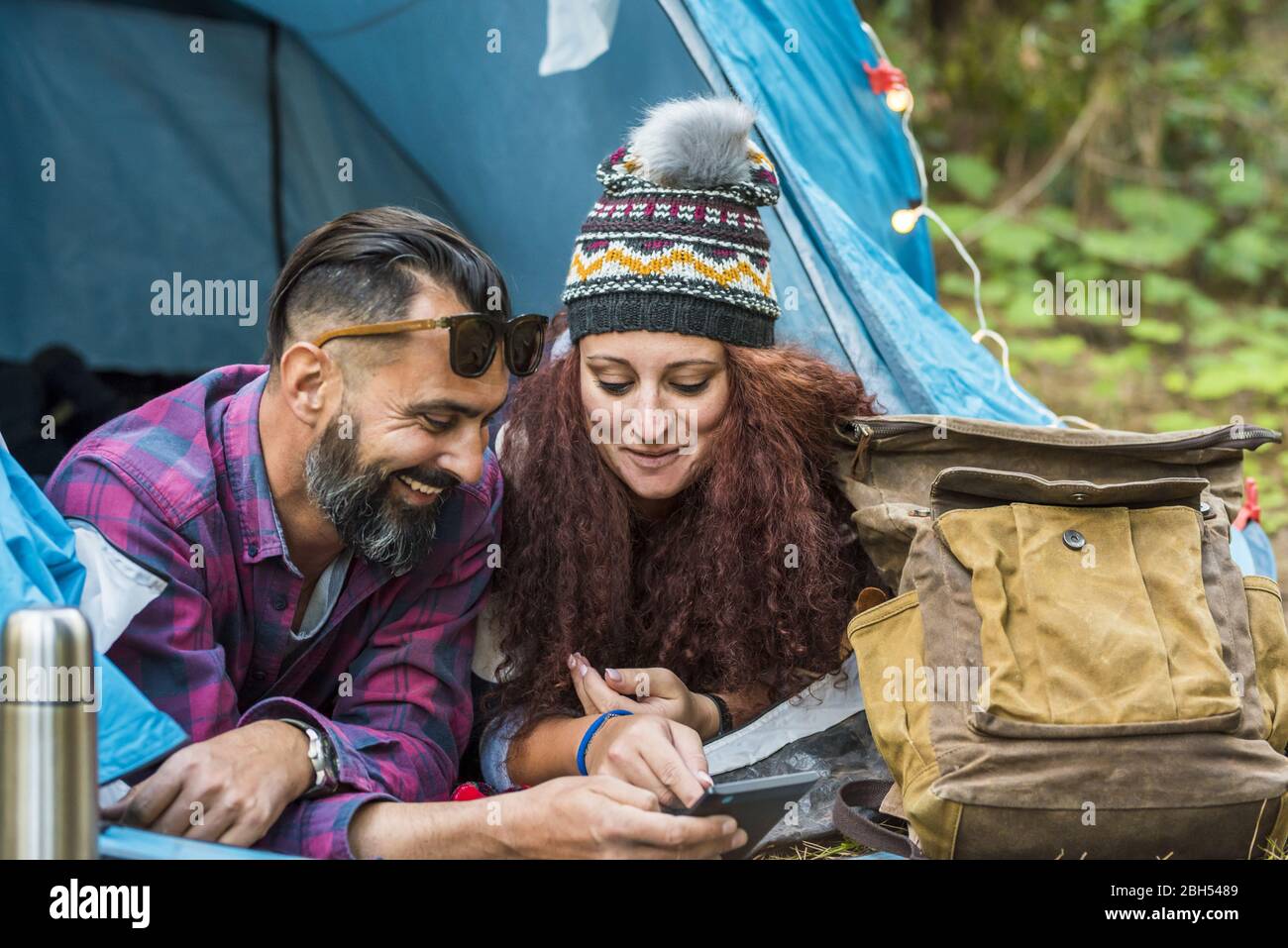 Smiling couple lying in tent using tablet Stock Photo