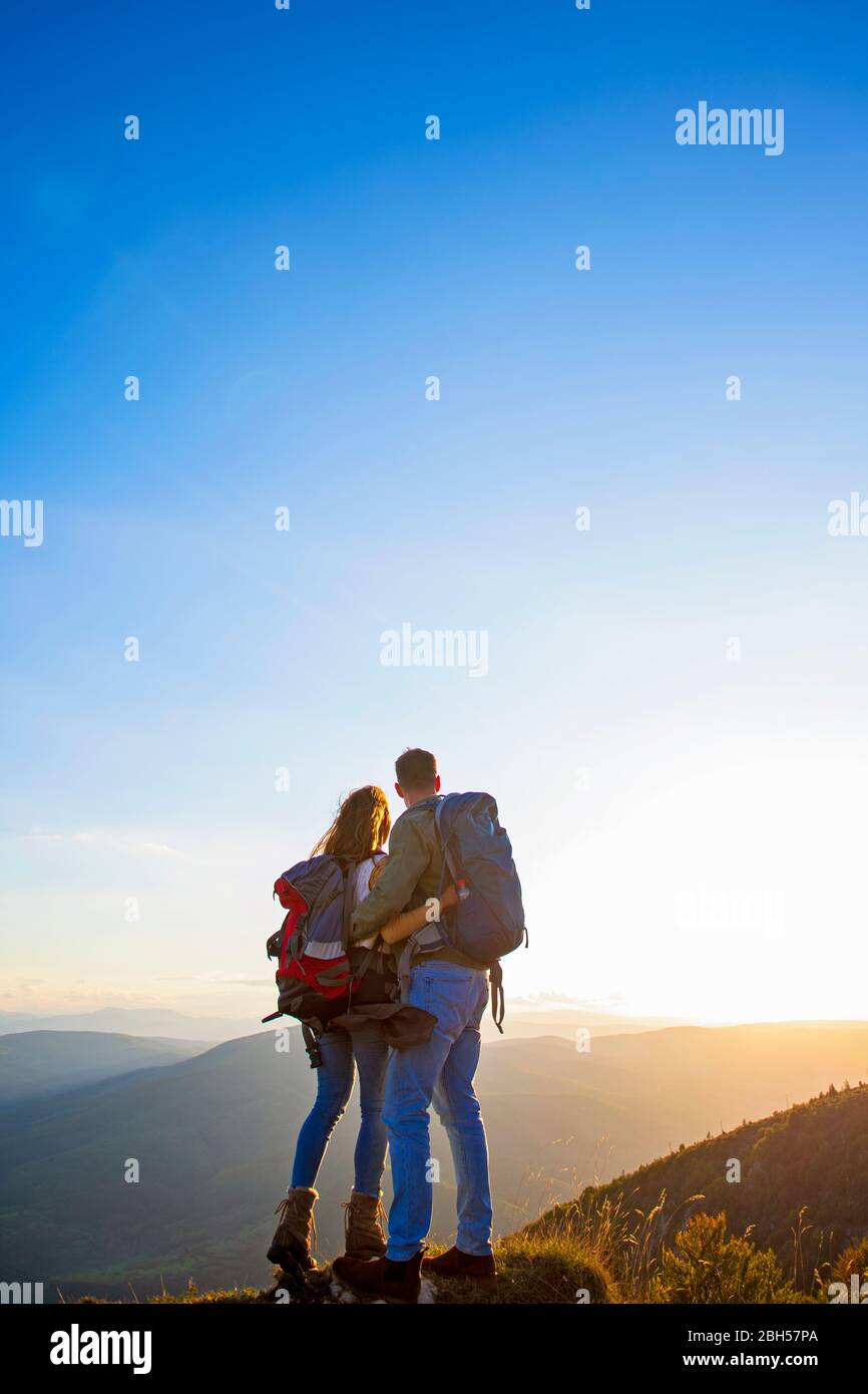 Hikers with backpacks relaxing on top of a mountain and enjoying the ...