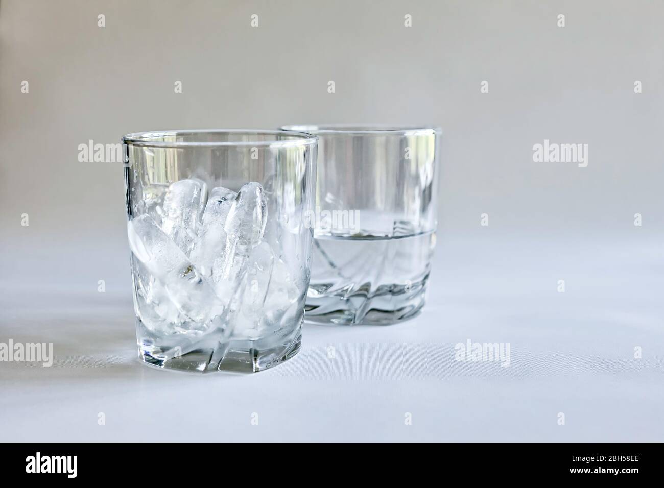 https://c8.alamy.com/comp/2BH58EE/profile-view-of-drinking-glasses-of-ice-and-water-melted-ice-in-transparent-tumblers-on-a-neutral-background-concepts-of-time-and-change-color-2BH58EE.jpg