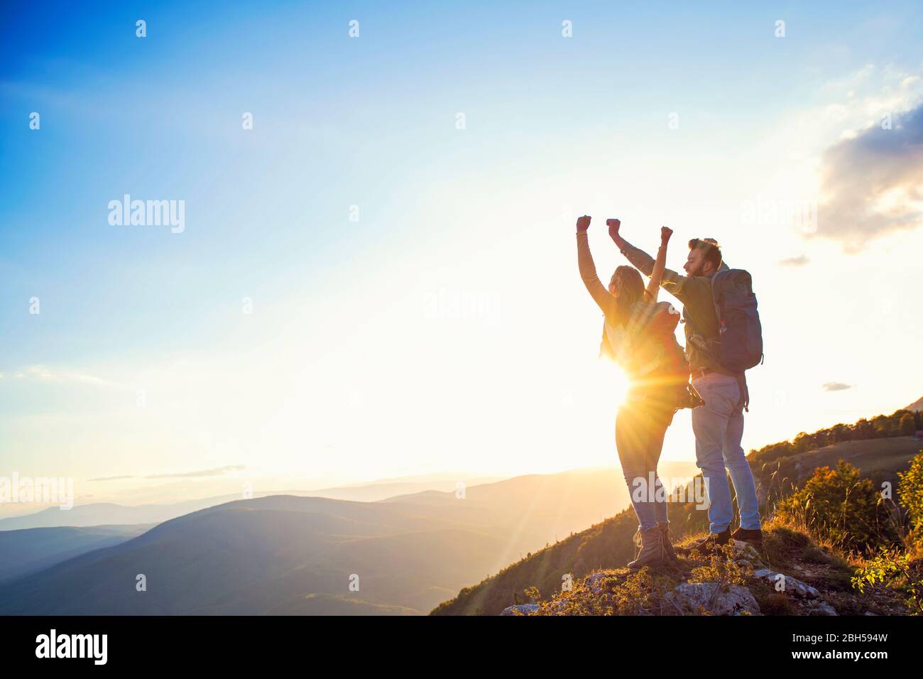 happy couple man and woman tourist at top of mountain at sunset ...