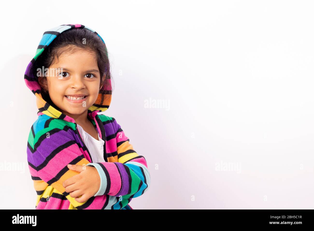 Little girl with cute face with her colorful sweater, with a white background Stock Photo