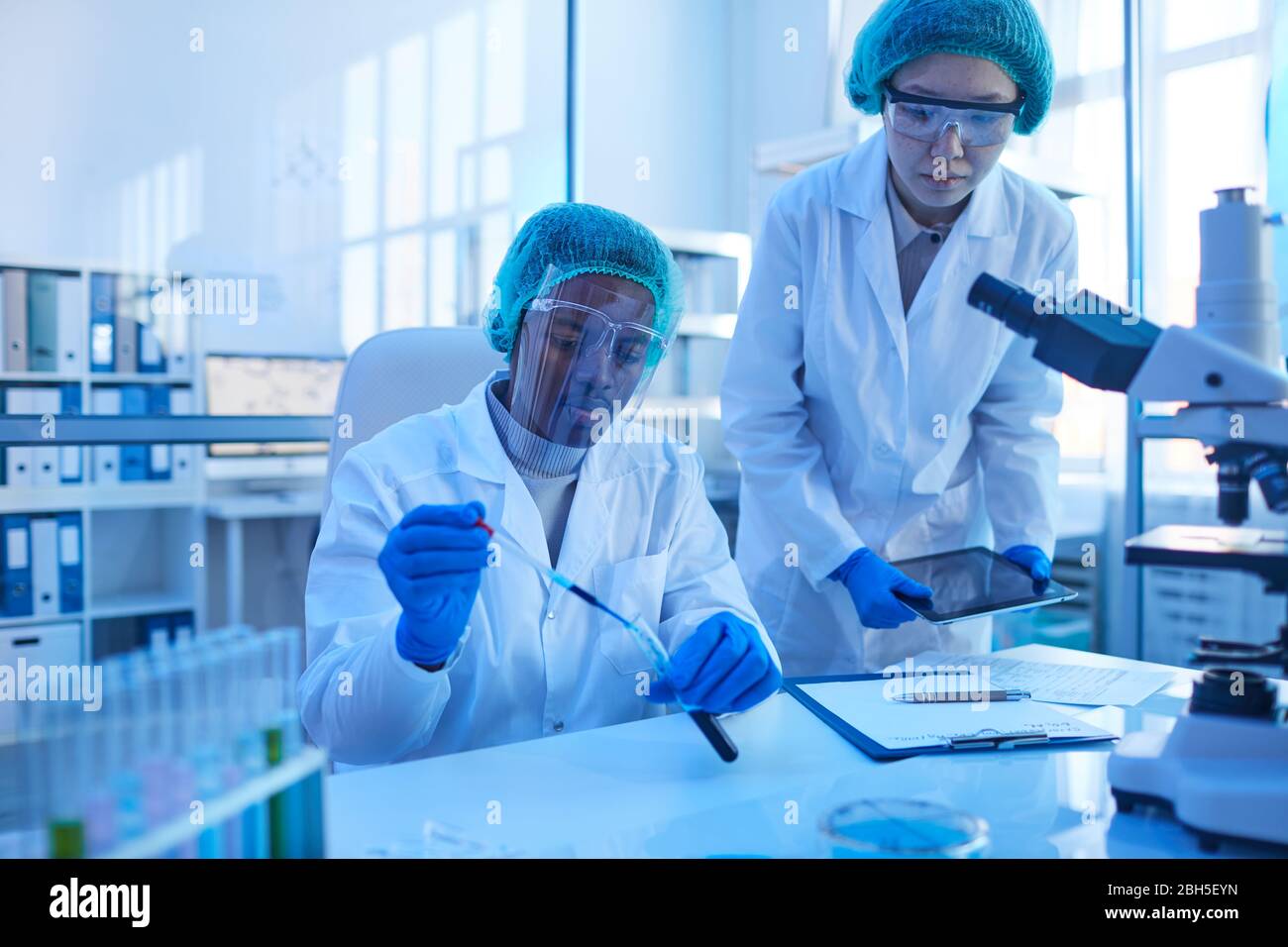 Two scientists working in team at the table they examining samples in test tubes Stock Photo