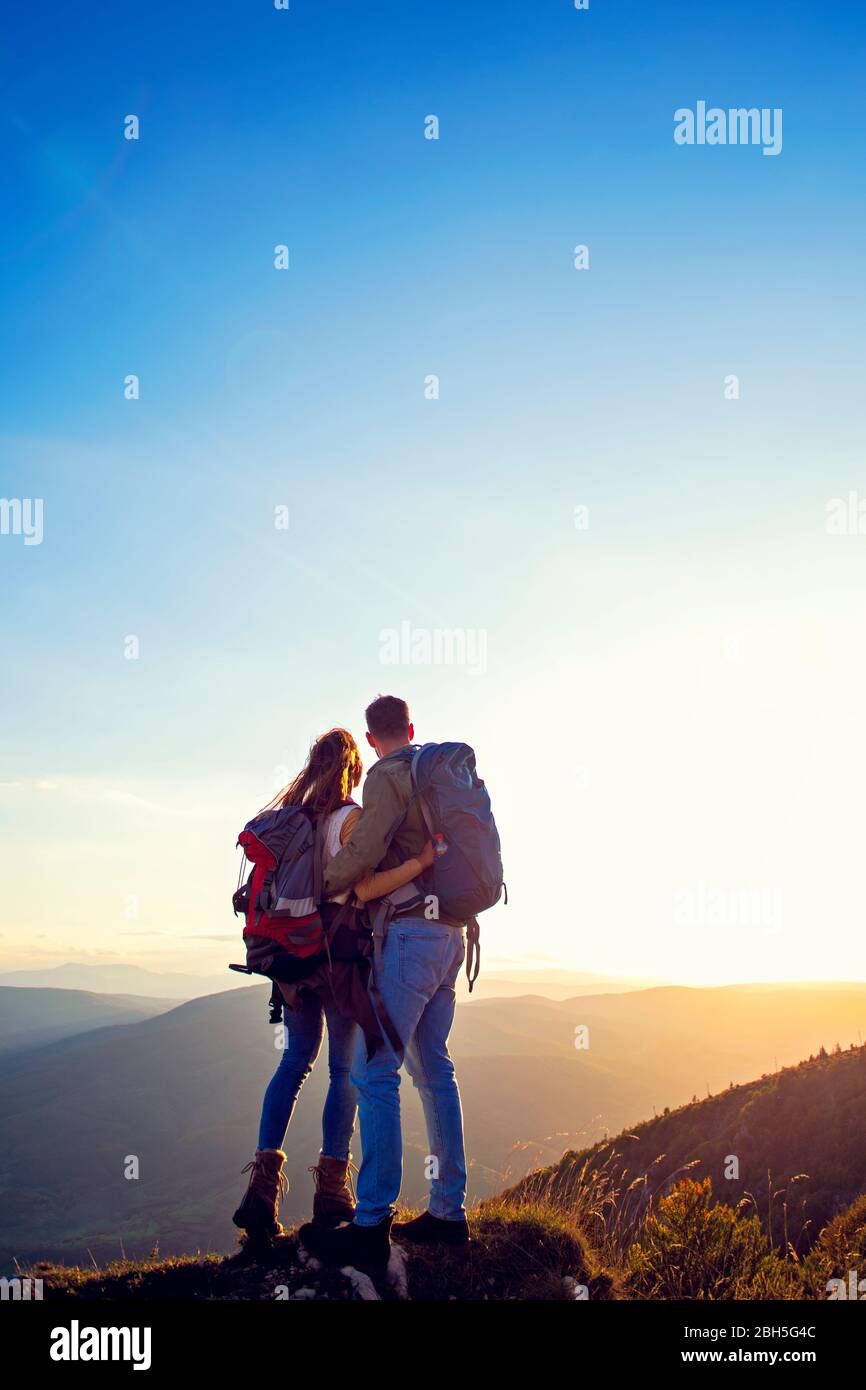 Hikers with backpacks relaxing on top of a mountain and enjoying the ...