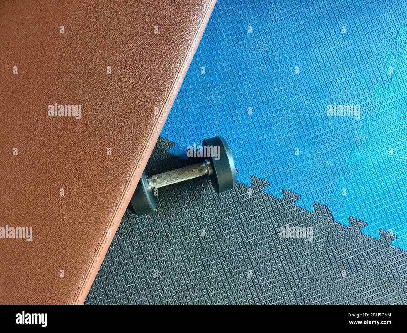 The photo of TThe blue and black rubber gym floor with a dumbell and a