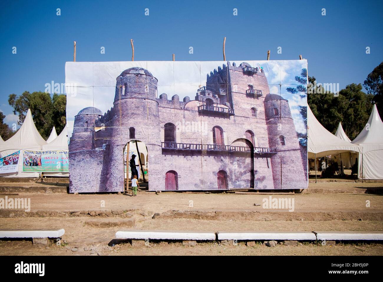 A little boy walks through a giant image of Fasilides castle at a Timkat festival ground. In Gondar, Ethiopia, Africa. Stock Photo