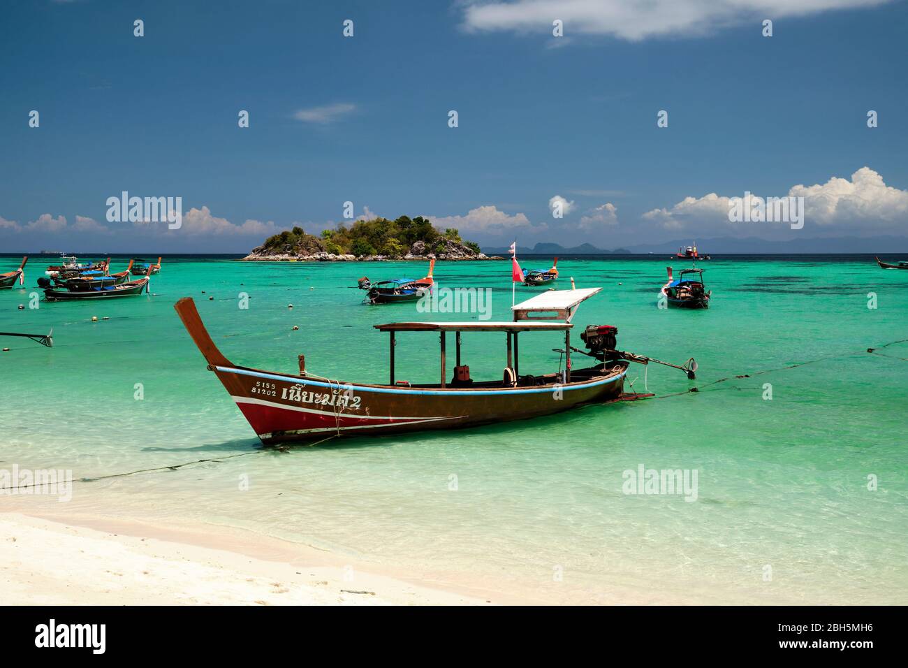 Taxi boat on sunrise beach thailand asia, with clear blue water and blue sky, koh usen island in the background. Stock Photo