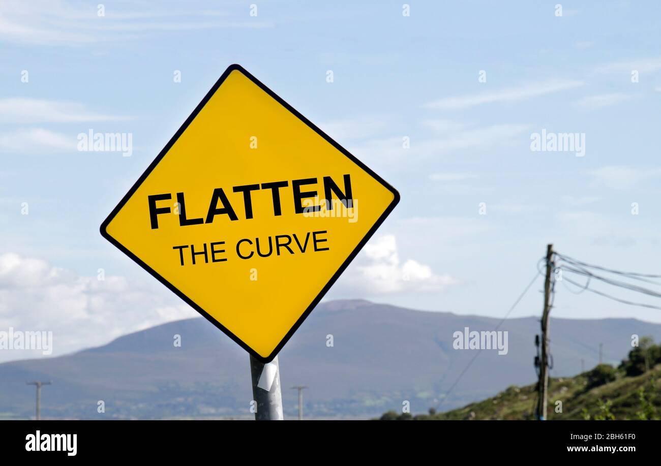 Yellow road sign with the words 'Flatten the Curve' written on it Stock Photo