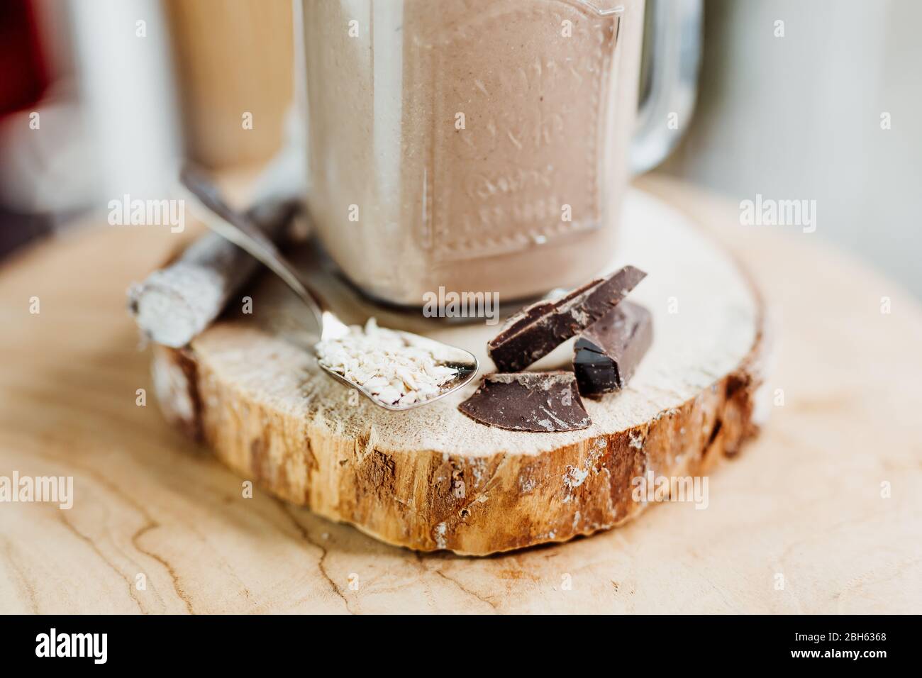 Healthy protein shake with banana, peanut butter, oats and agave syrup in a stylish glass, decorated with chocolate protein, oatmeal and mint Stock Photo