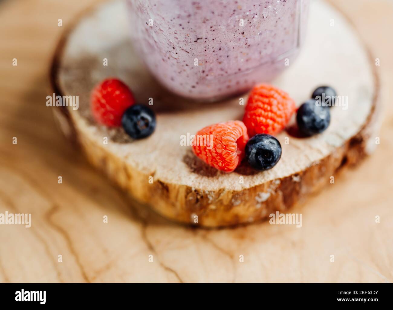 Healthy vitamin shake with dragon fruit, berries, chia seeds and almond milk in a stylish glass, decorated with raspberry and blueberry Stock Photo