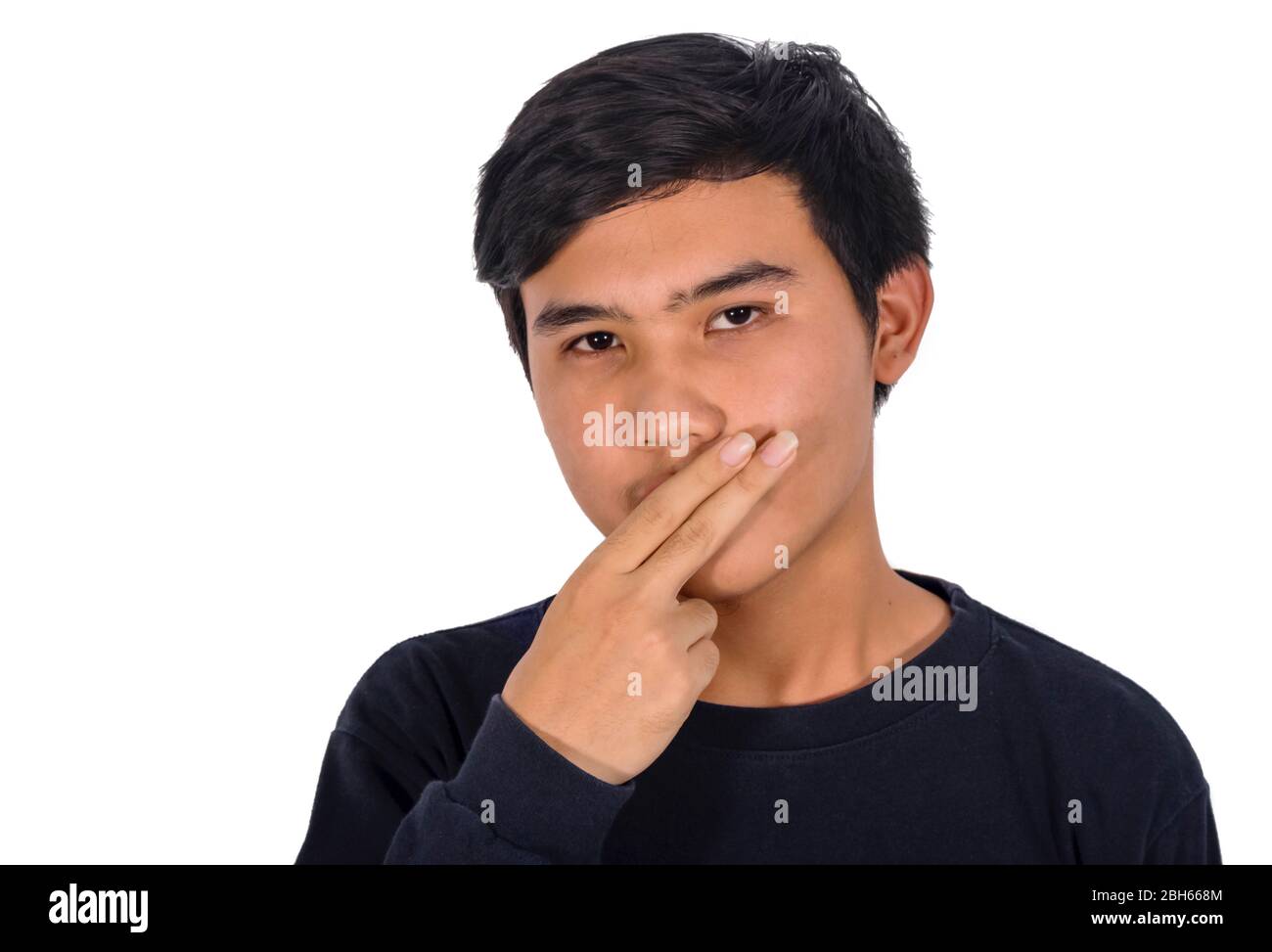 The photo of a boy closes his mouth with his two fingers points to the copy space Stock Photo