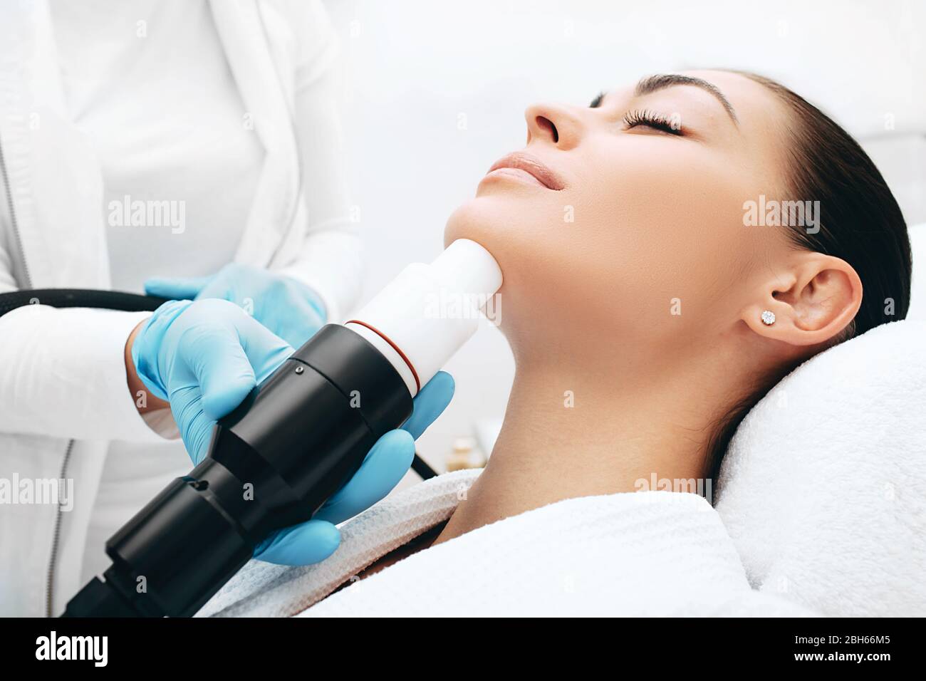 Beautician doing an acoustic wave therapy to a woman. Skin rejuvenation with acoustic waves, close-up face Stock Photo