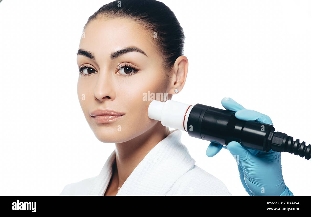 doctor doing an acoustic wave therapy to a woman. Skin rejuvenation with acoustic waves. Portrait women on a white background Stock Photo