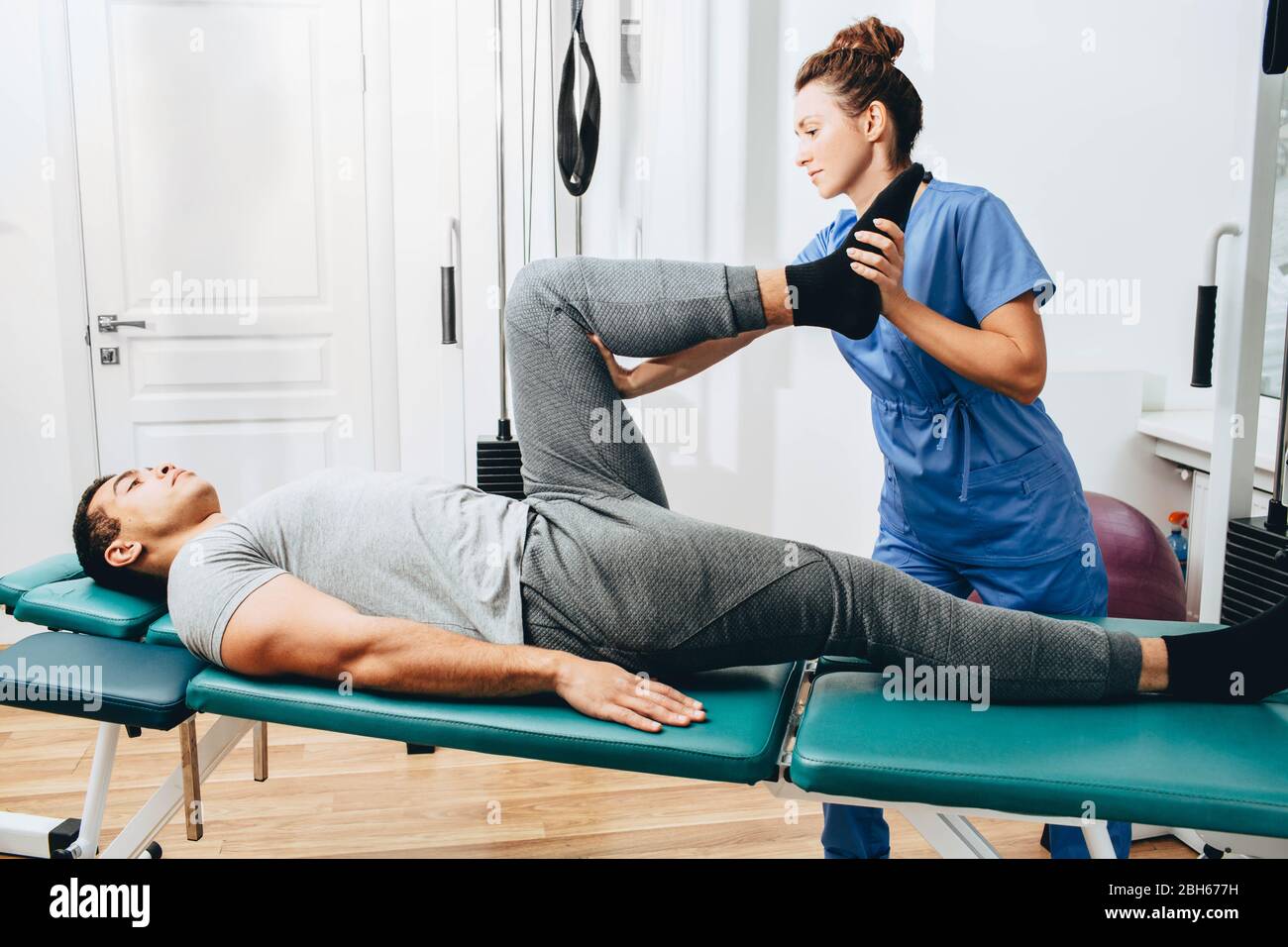 Treatment of a knee injury to a patient in a hospital. Exercises to restore the knee. Physiotherapist examines leg condition Stock Photo