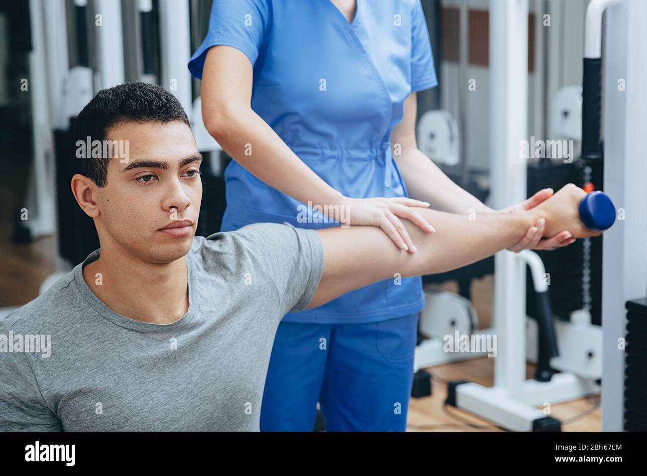 Mixed race man training hand, holding dumbbells,his physiotherapist help him to rehabilitation Stock Photo