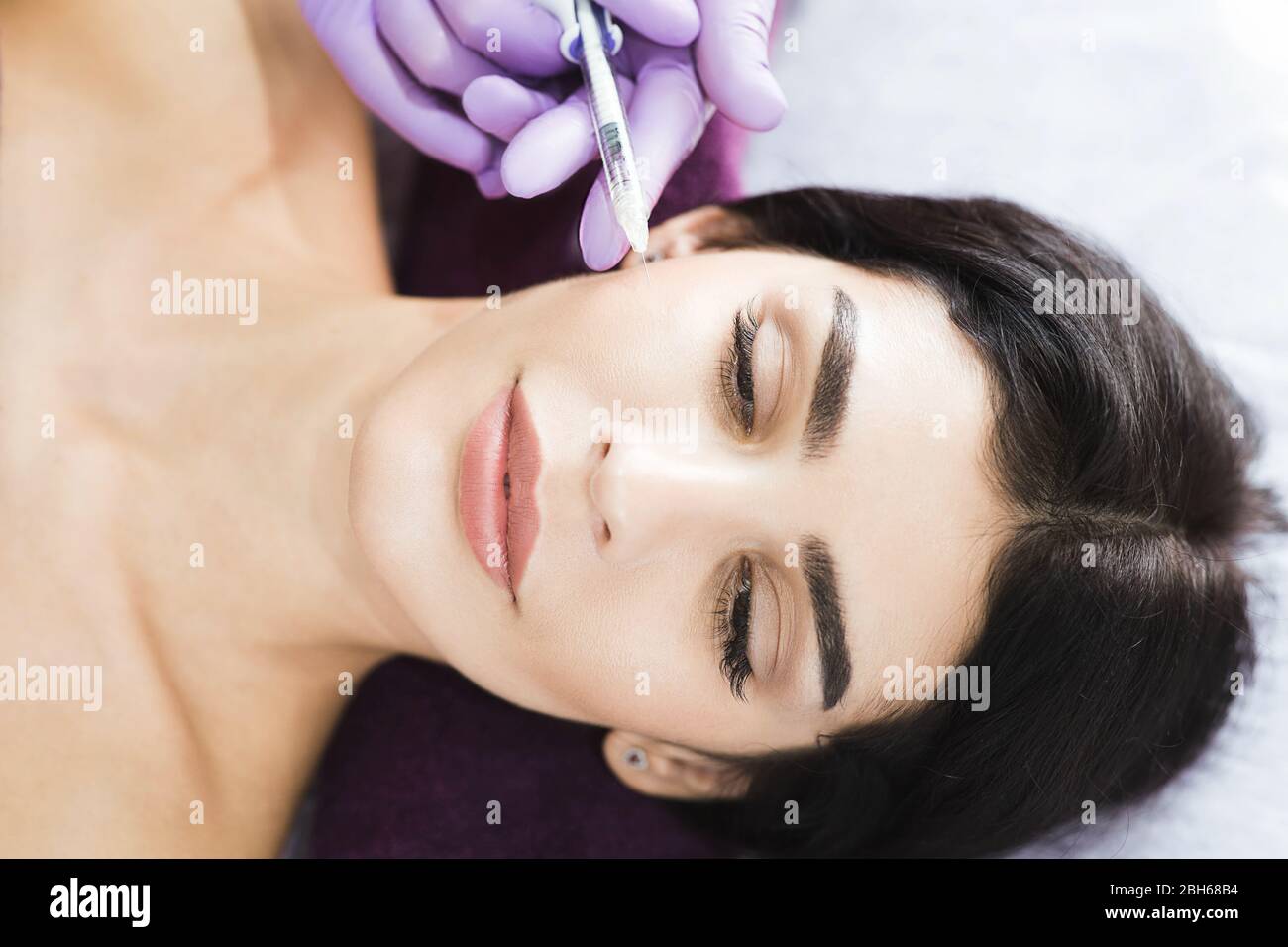 Beauty injections close up. A beautiful mid-aged brunette gets injections of beauty, anti wrinkles therapy, skin rejuvenation Stock Photo