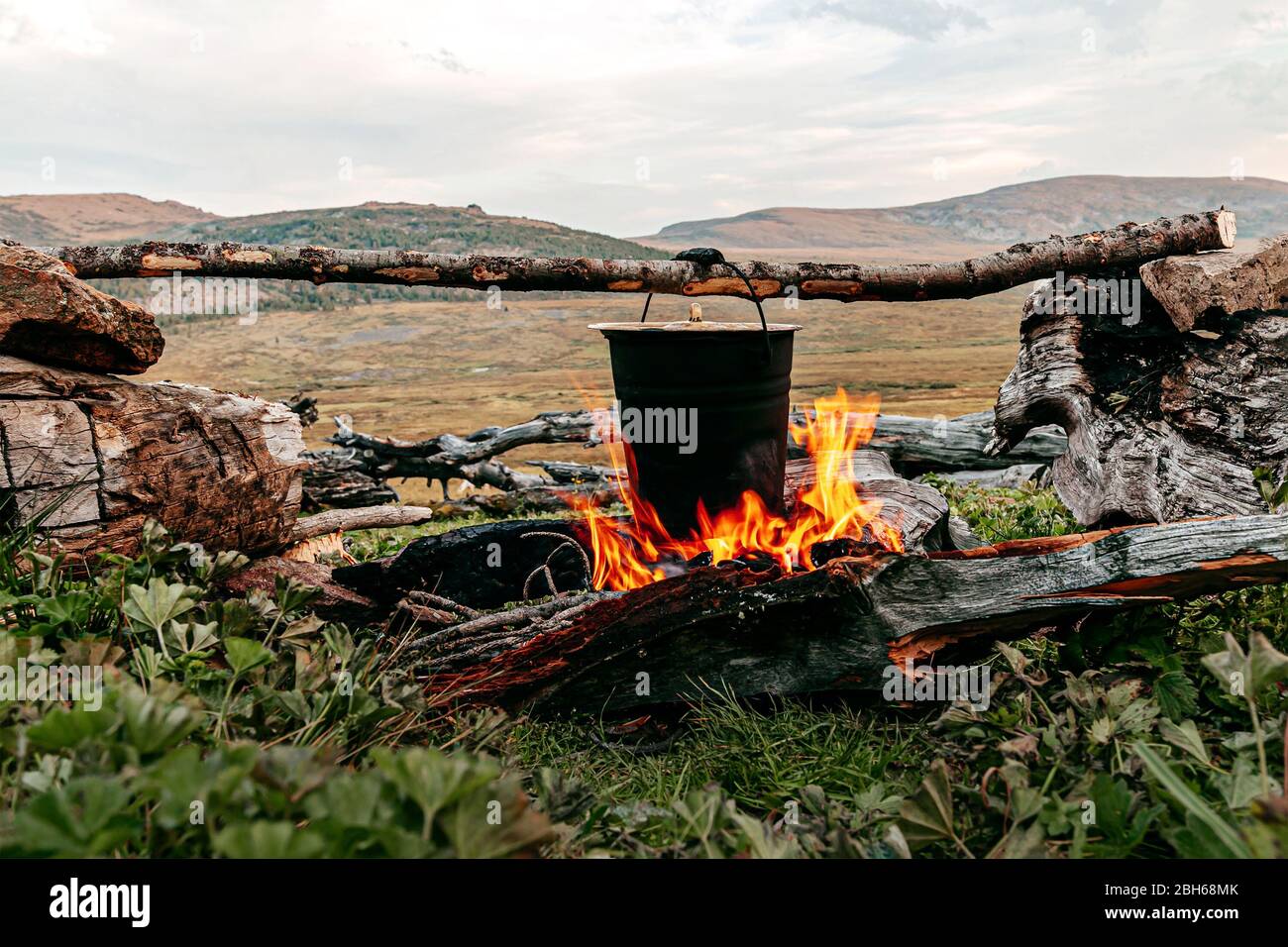 cooking food in pot on burning camp fire during mountain tour Stock Photo