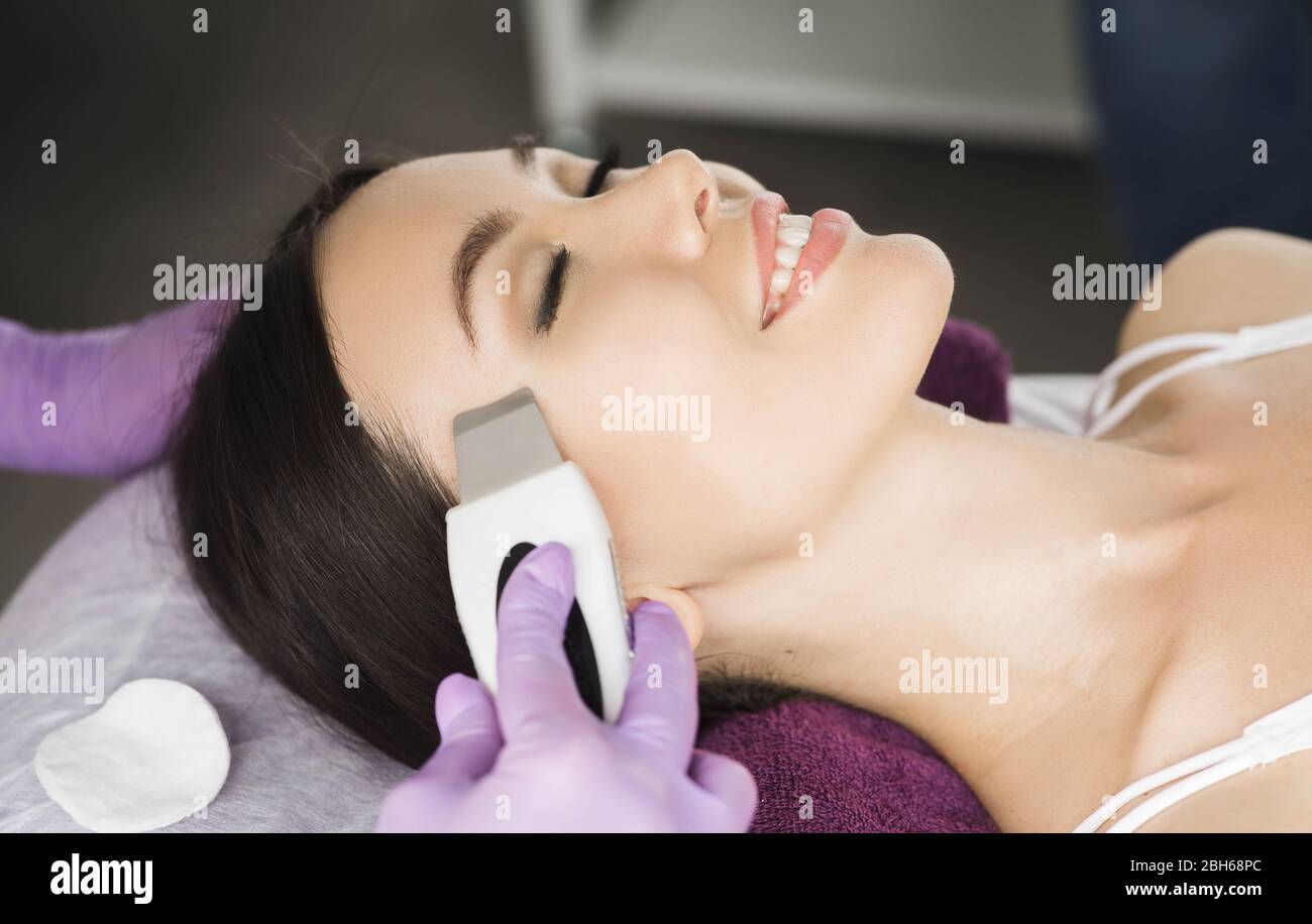 asian woman receiving ultrasound cavitation facial peel. get clean face without blackheads and skin defects using ultrasound equipment Stock Photo