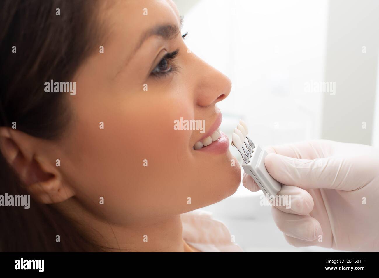 dentist with teeth color samples, choosing shade for woman teeth at dental clinic. Whitening teeth Stock Photo