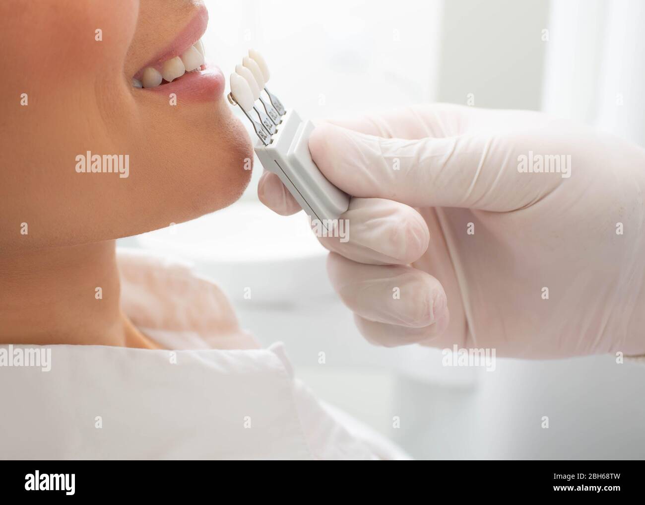 dentist with teeth color samples, choosing shade for woman teeth at dental clinic. Whitening teeth Stock Photo