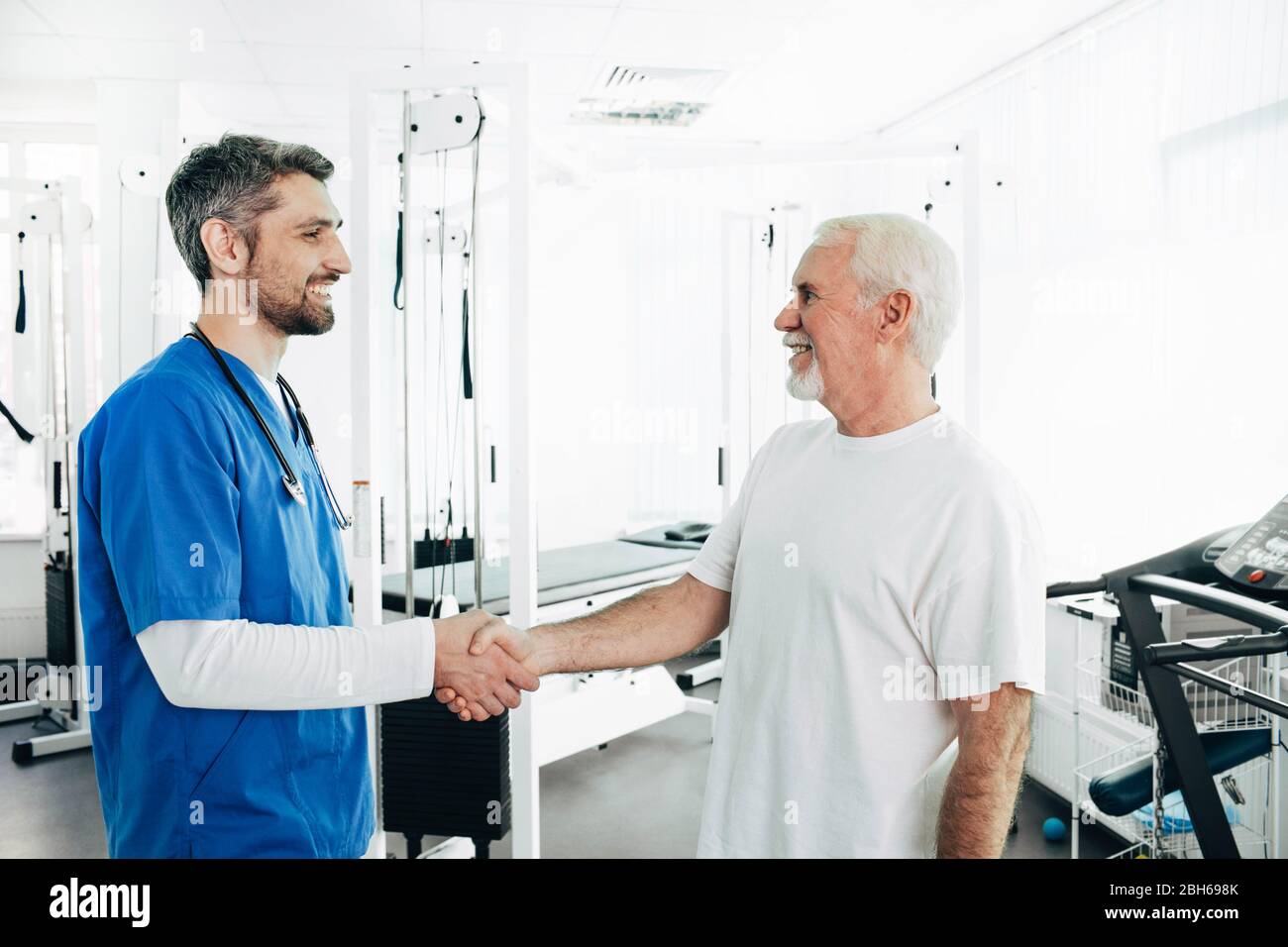 Senior man and Physical Therapist handshake after successful physio treatment. Stock Photo