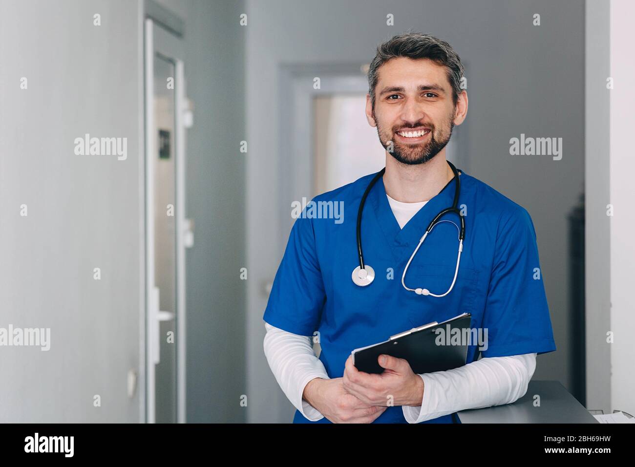 male nurse with stethoscope standing at clinic. He is smiling and looking at the camera. Stock Photo