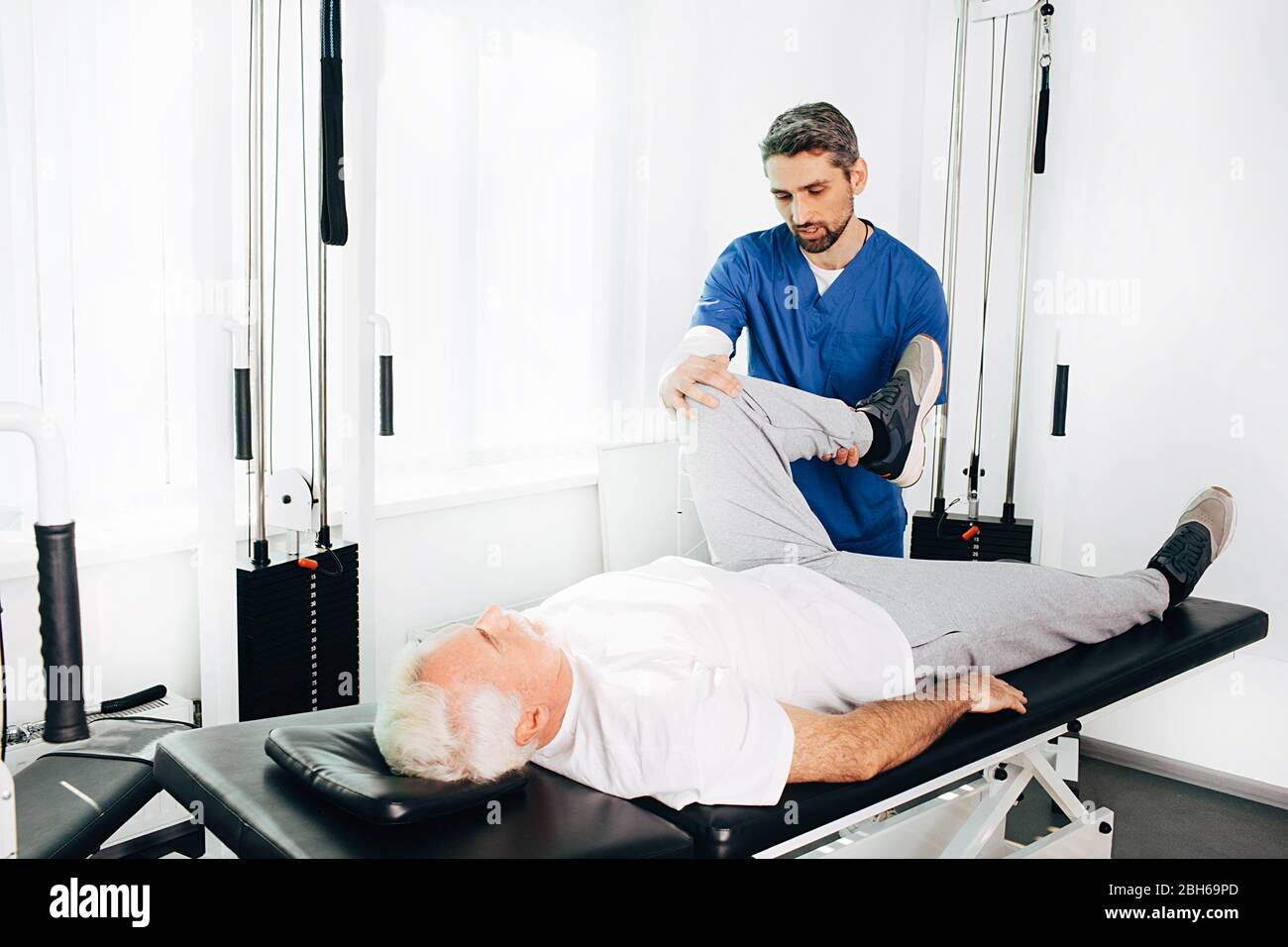 physiotherapist assisting a senior patient in recovery at wellness center. Stock Photo