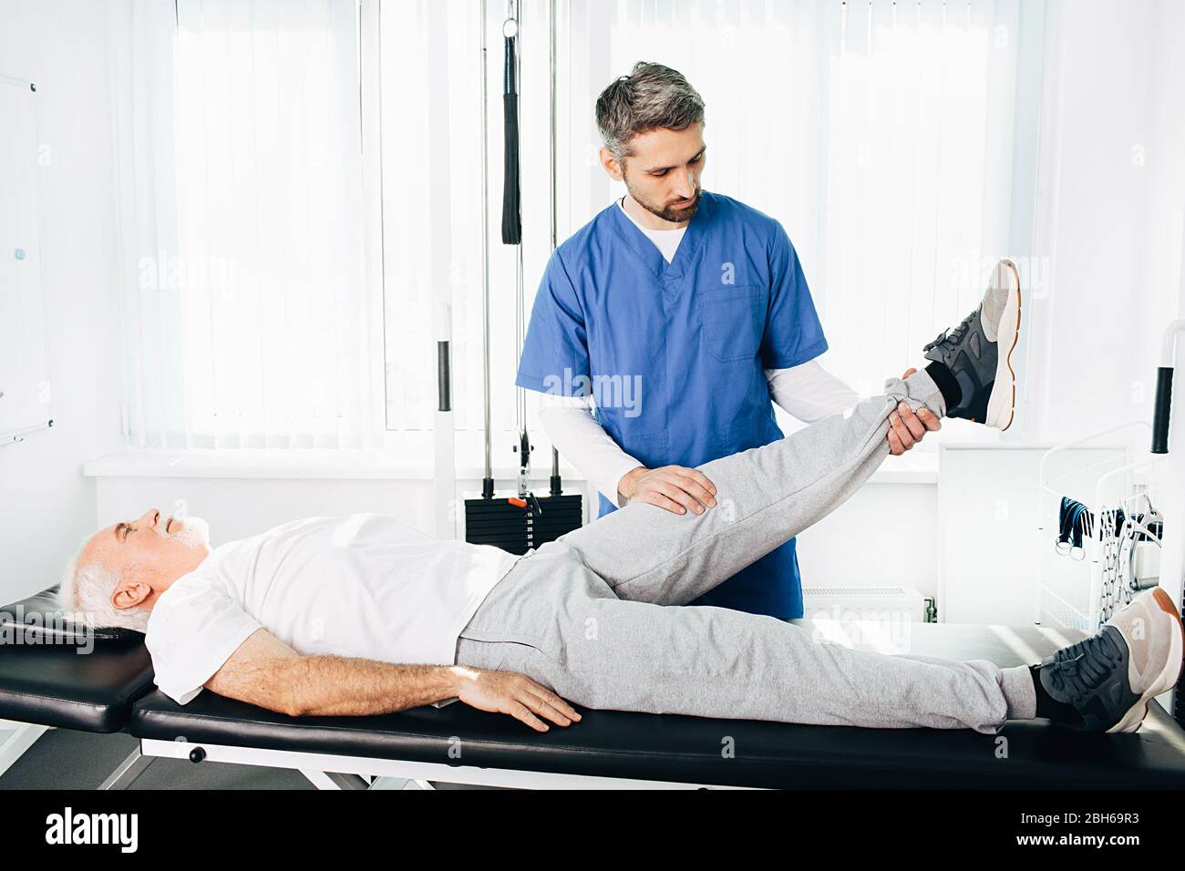physiotherapist assisting a senior patient in recovery at wellness center. Stock Photo