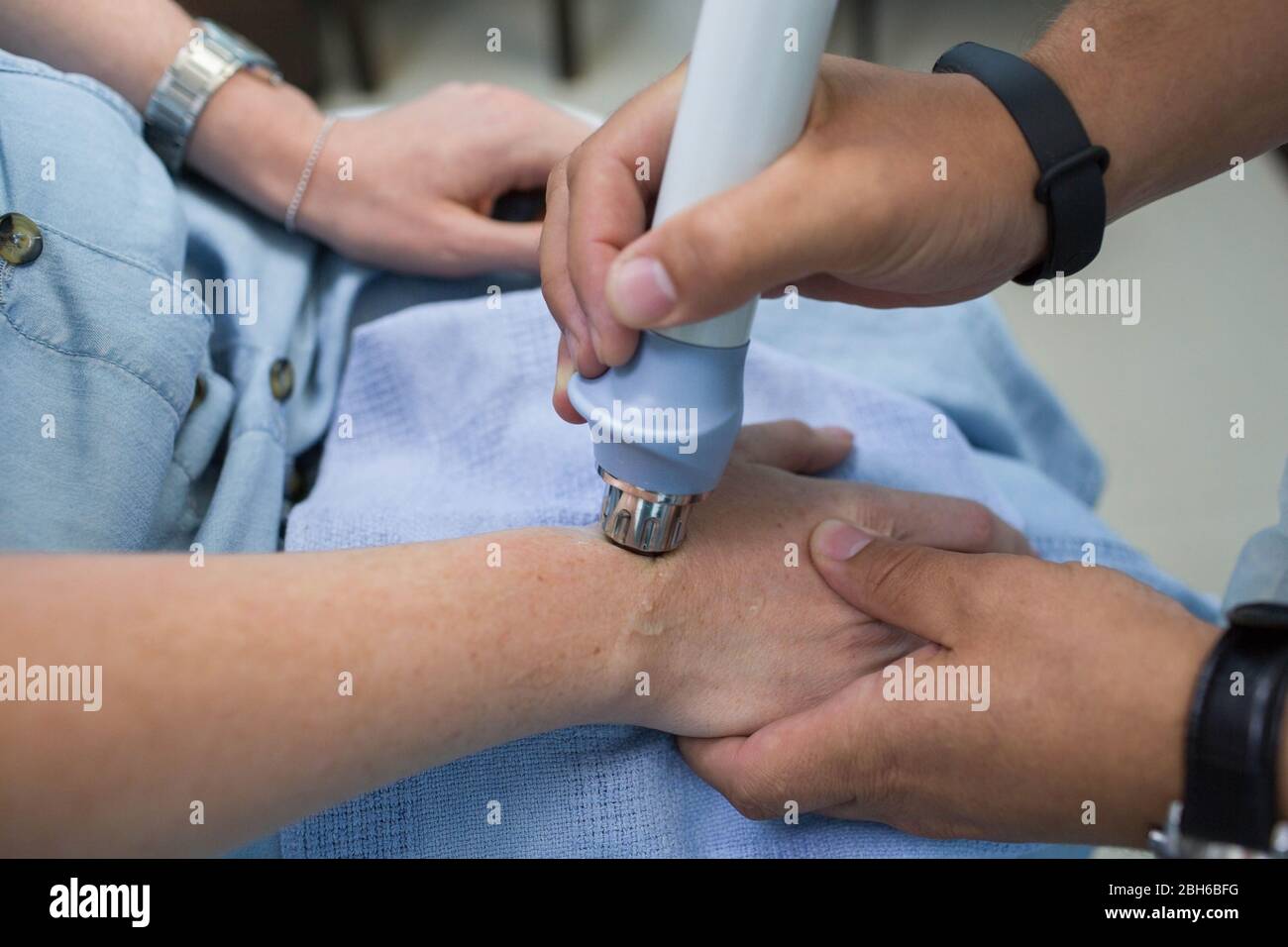 Procedure shock wave therapy at clinic. Physiotherapist treatment pain on the arm with shock wave equipment Stock Photo
