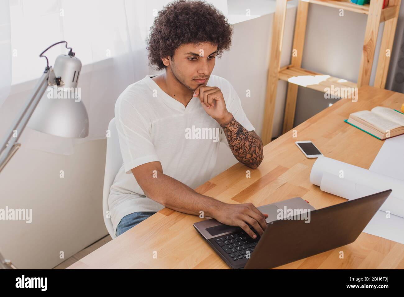 Work at home on laptop. Attractive man arabian nationality concentrated looking at the laptop and thinking. Stock Photo