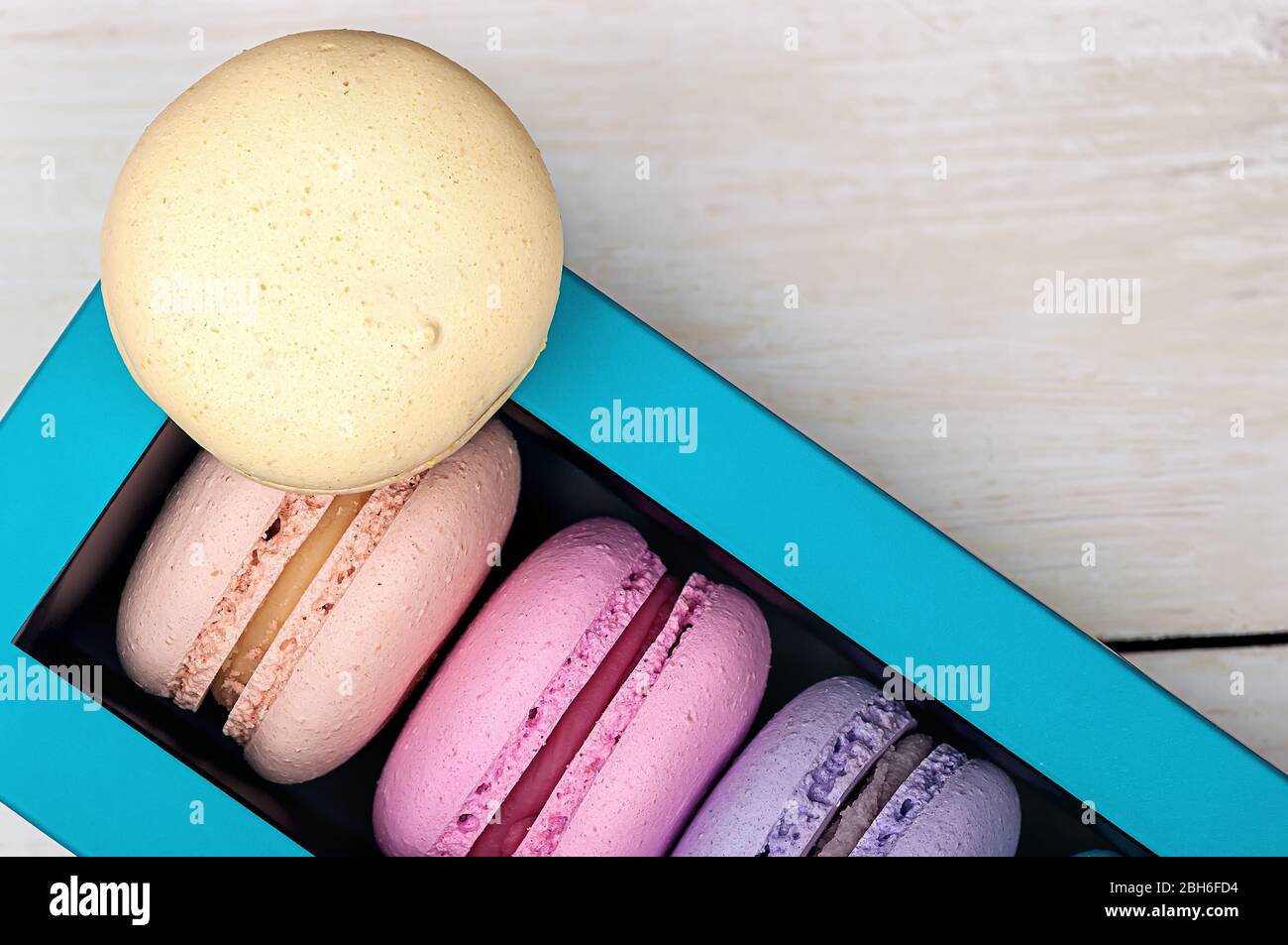Macaroons in box and one on top Stock Photo
