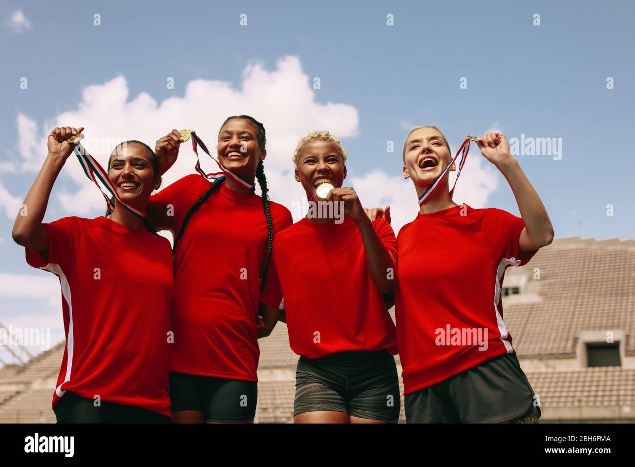Female soccer players with medals after winning the championship. Woman football team celebrating the victory at stadium. Stock Photo