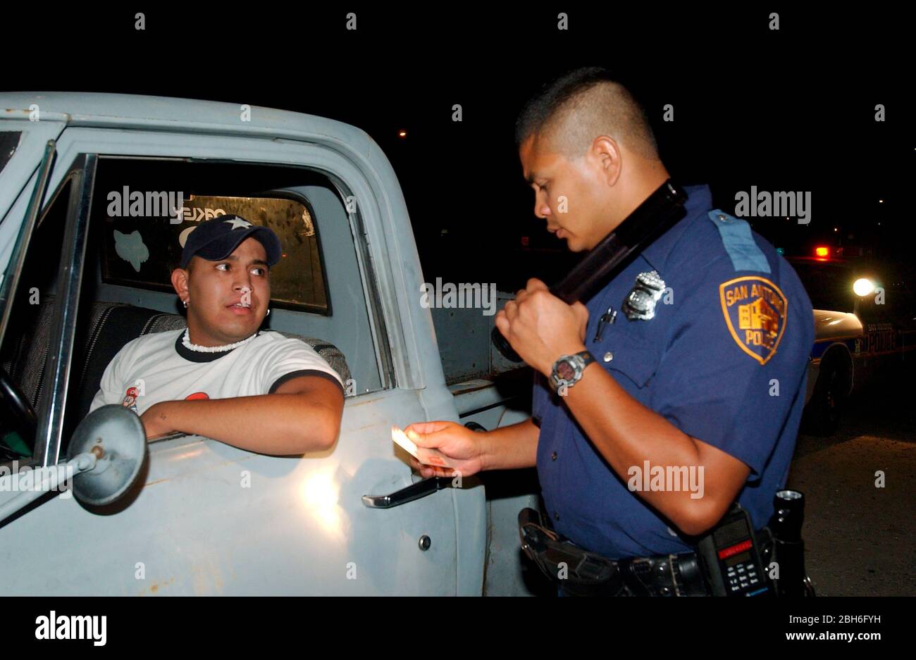 San Antonio, Texas USA, August 2003. Hispanic male police officer questions a driver who had an expired driver's license during an overnight shift.  ©Bob Daemmrich Stock Photo