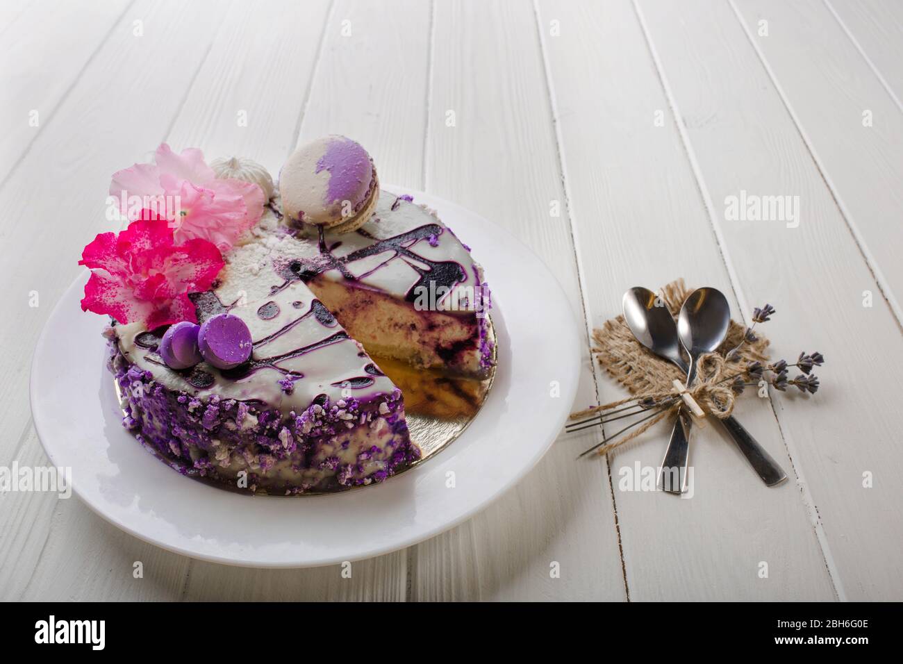 Homemade blueberry cheesecake decorated flower and macaroon on wooden white table background. Top view. Stock Photo