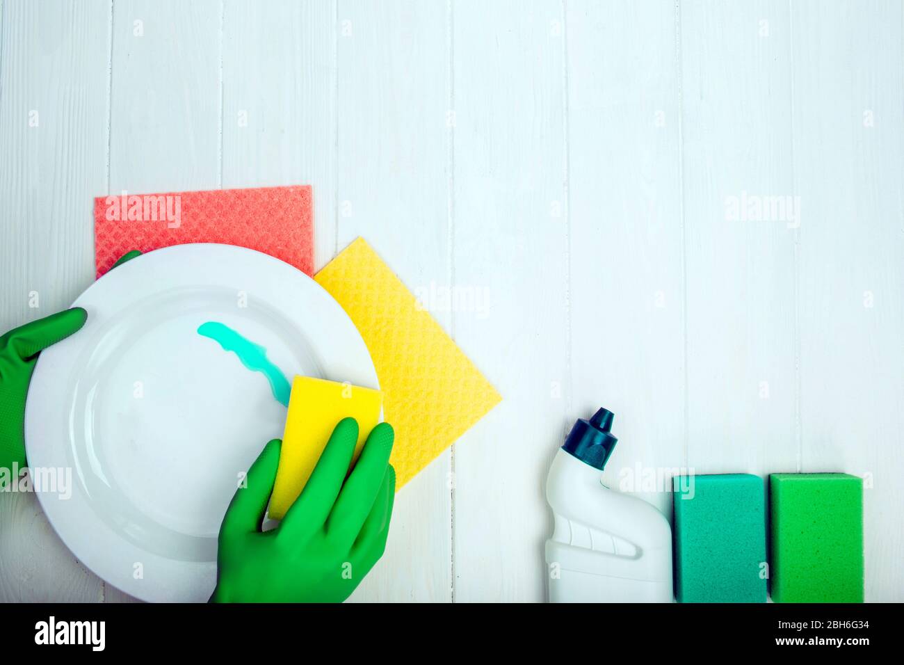 hands in rubber gloves washing dishes and cleaning detergent, top view Stock Photo