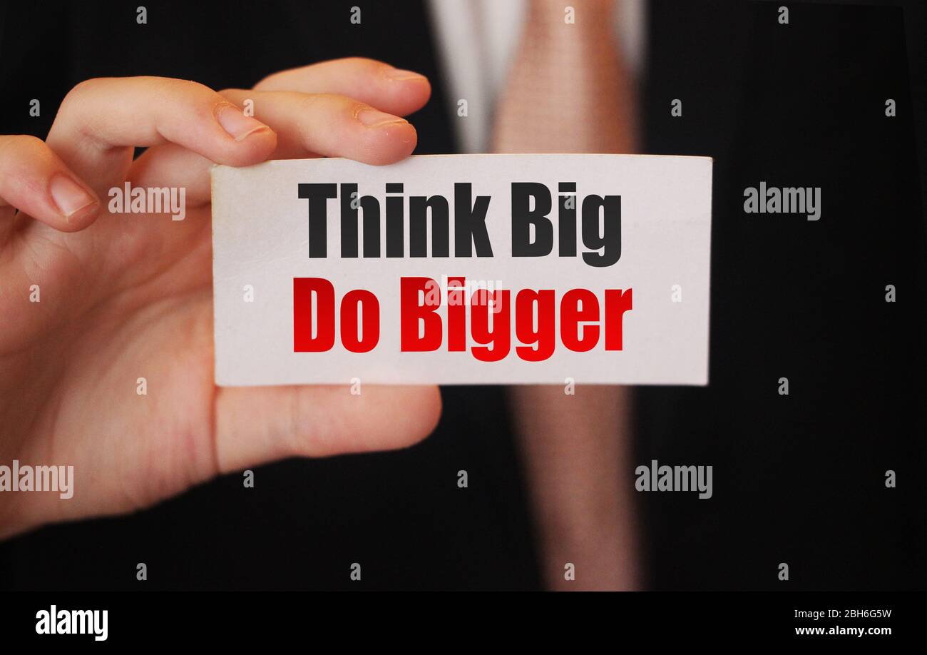 Think Big, Do Bigger. Motivation quote. Businessman holding a card with a message text written on it. Business concept Stock Photo