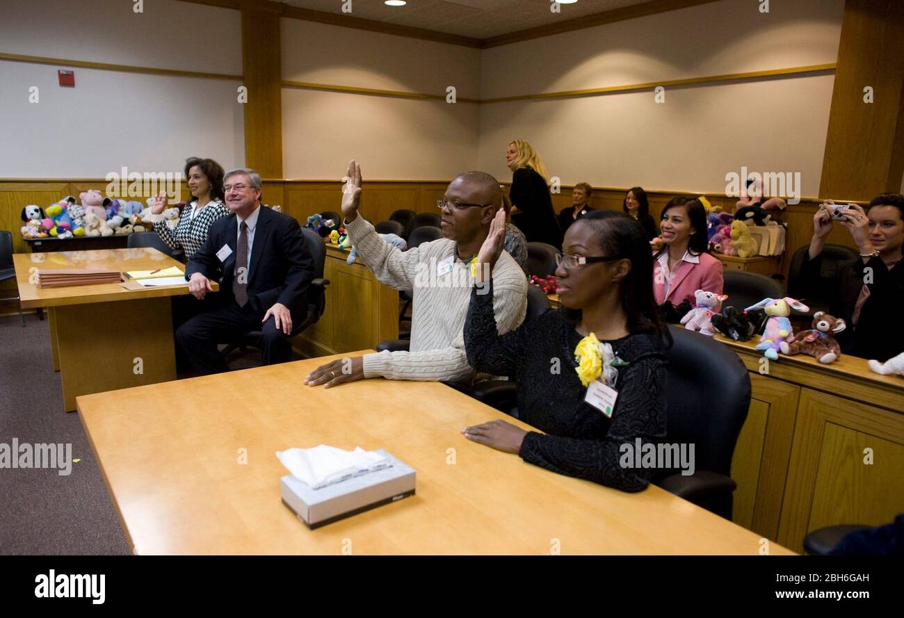 Austin, Texas November 20, 2008: Celebrating National Adoption Day in central Texas were 24 families who adopted children in festive ceremonies at the Travis County Juvenile Court. Anthony (c) and Penora Giles (r) take an oath in court.  ©Bob Daemmrich Stock Photo