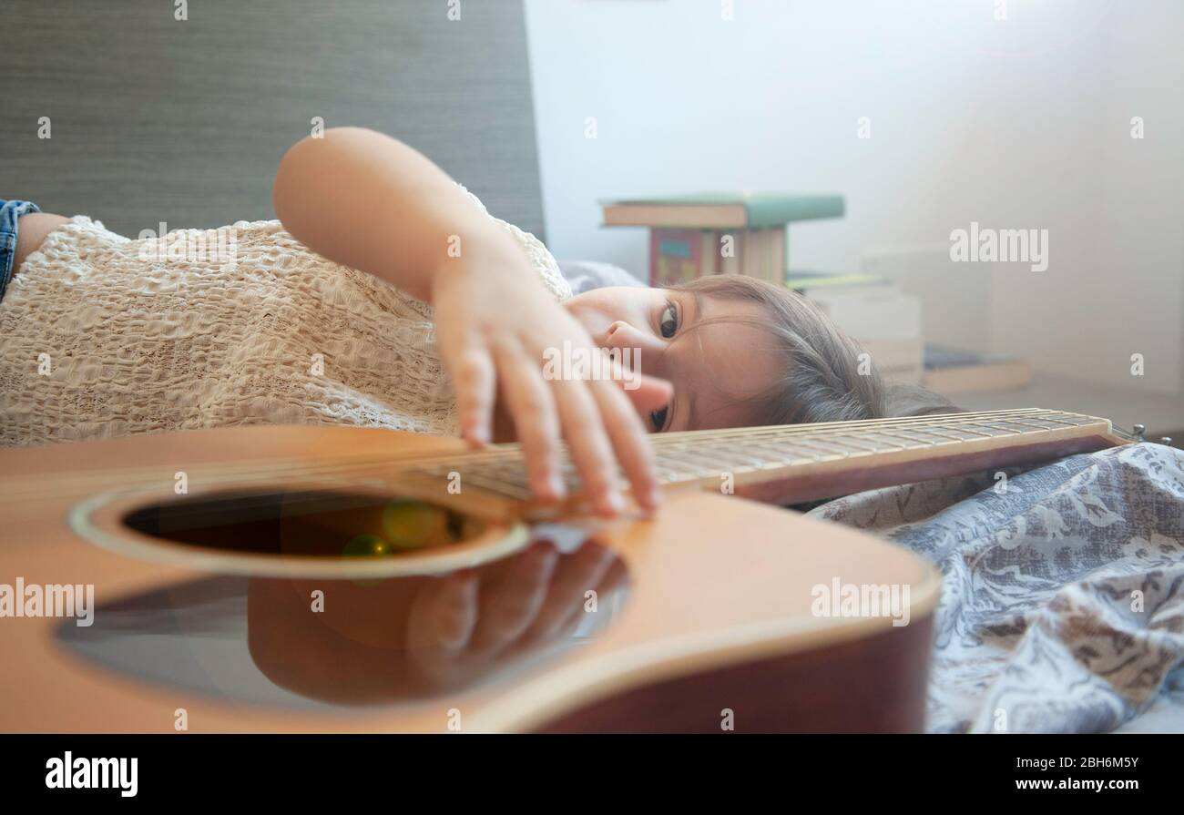 Little dreamer girl with beautiful eyes lying on the bed with her