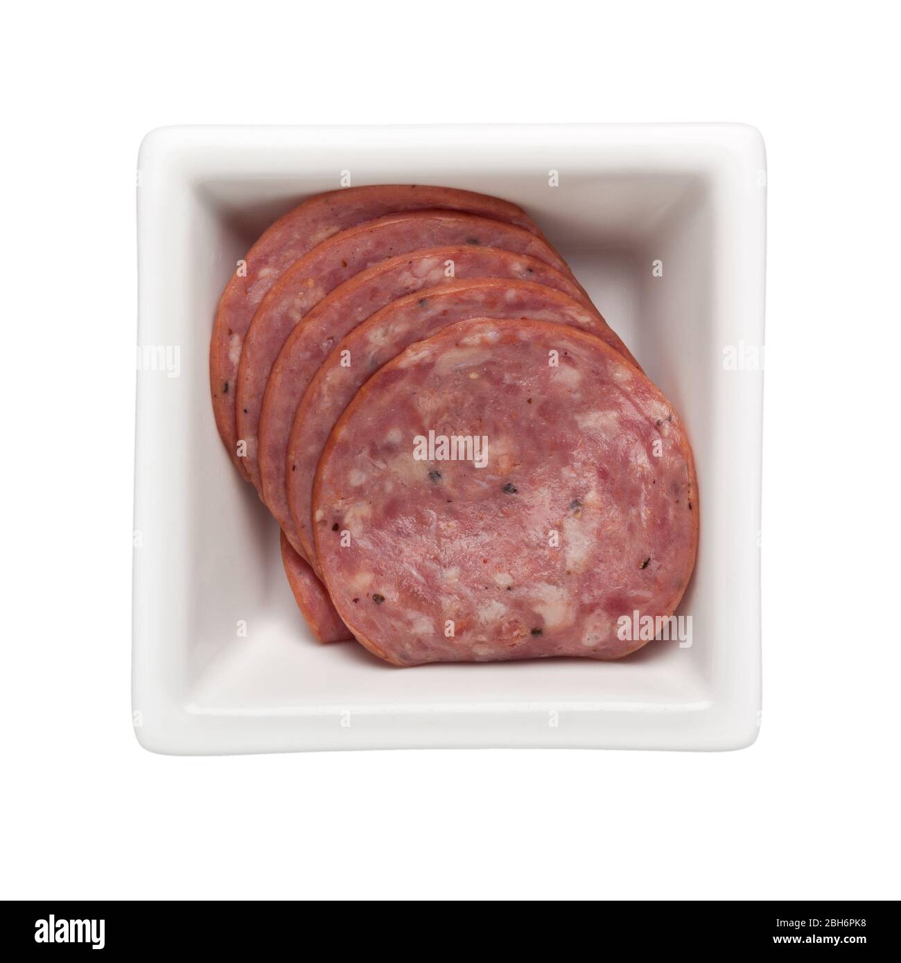 Slices of beef salami in a square bowl isolated on white background; Stock Photo