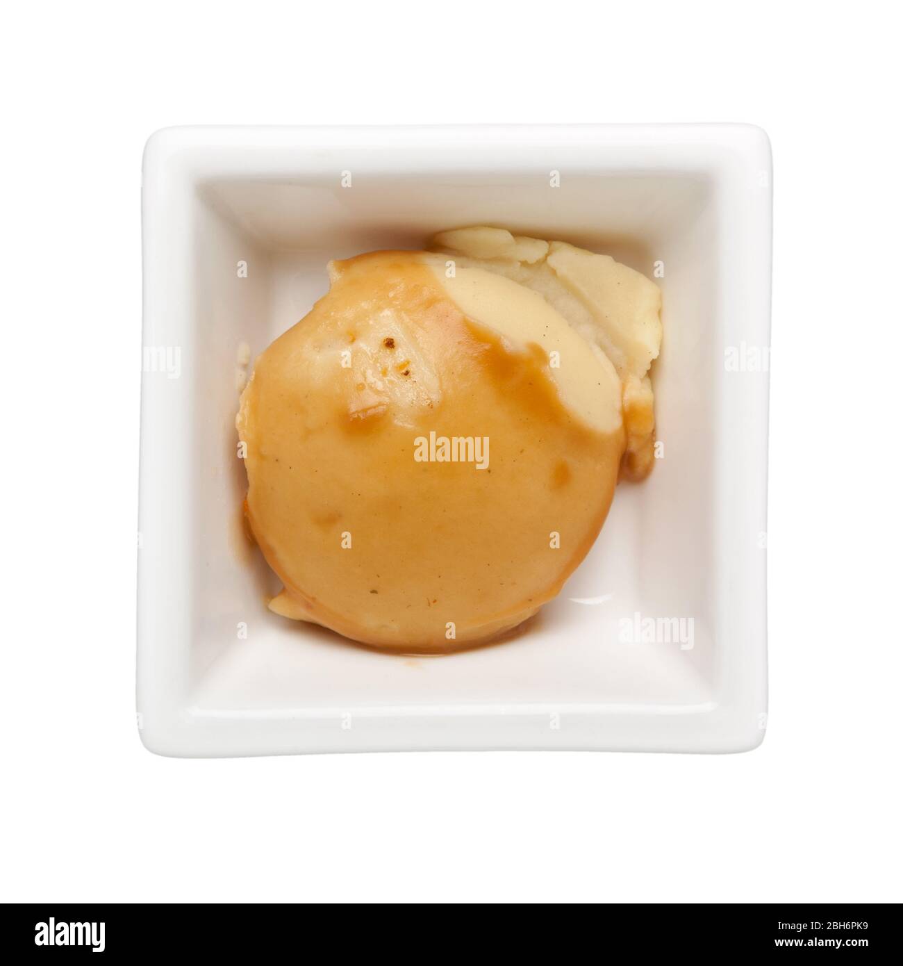 Serving of mashed potato with gravy in a square bowl isolated on white