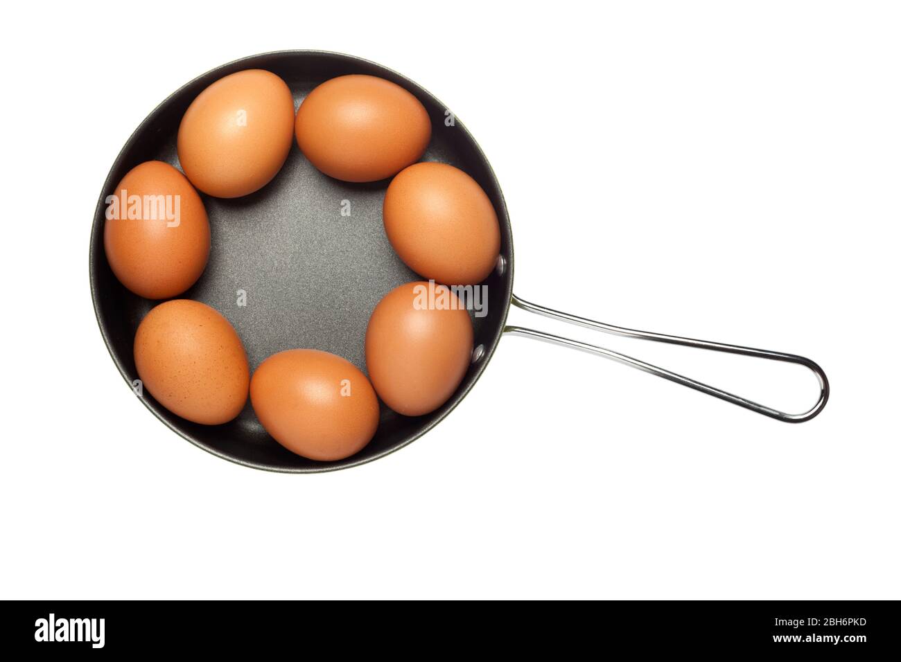 Frying pan with seven eggs arranged in a ring isolated on white background Stock Photo