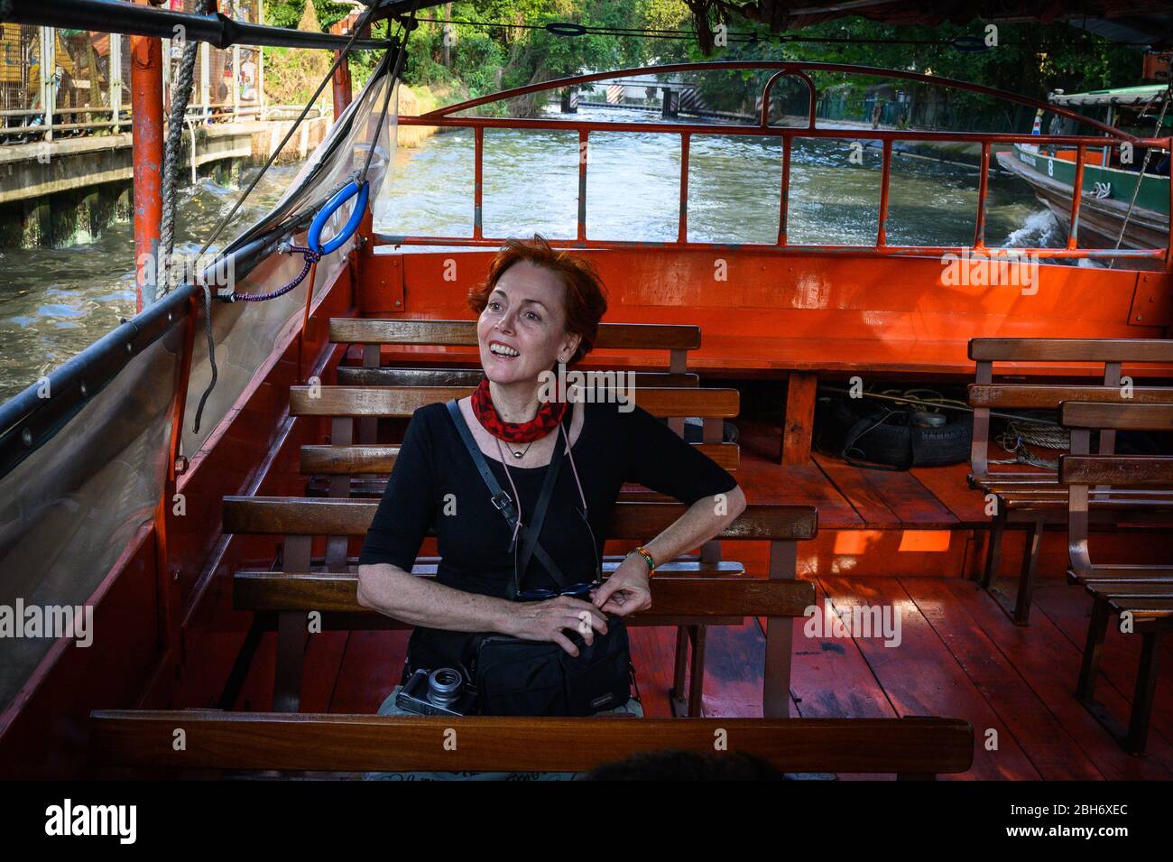 Western woman enjoying a boat ride through the canals of Bangkok, Thailand Stock Photo