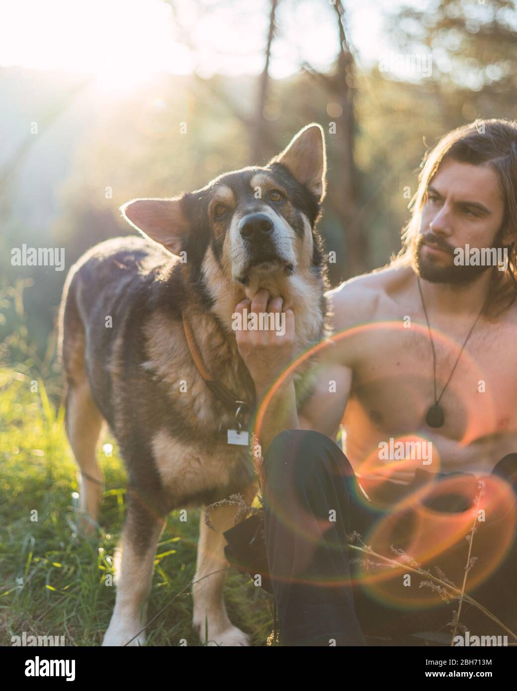 Portrait of a bearded man with his old dog and a beautiful sunset on the mountain Stock Photo